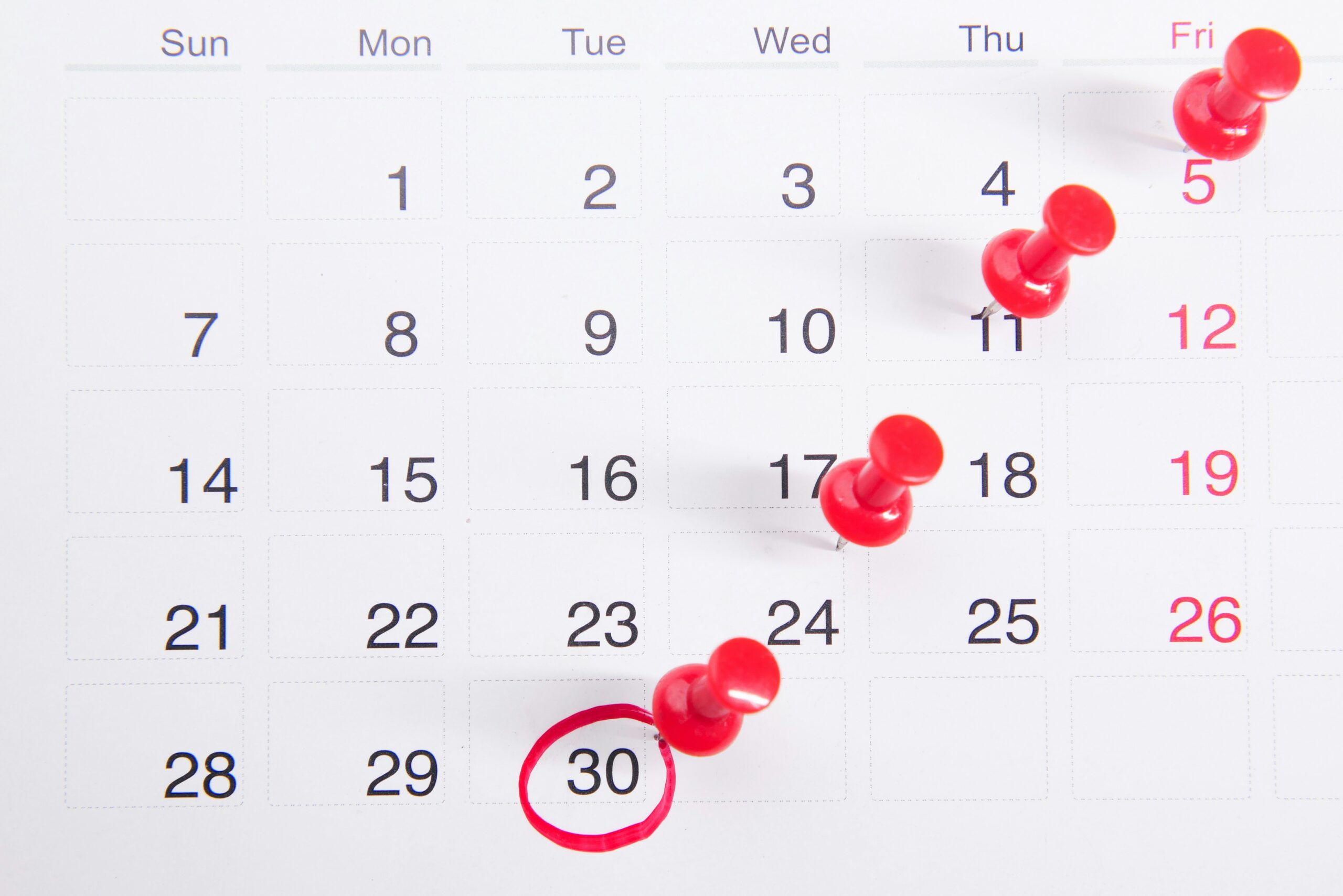 Calendar with red push pins in it. Tuesday the 30th is circled in red. 